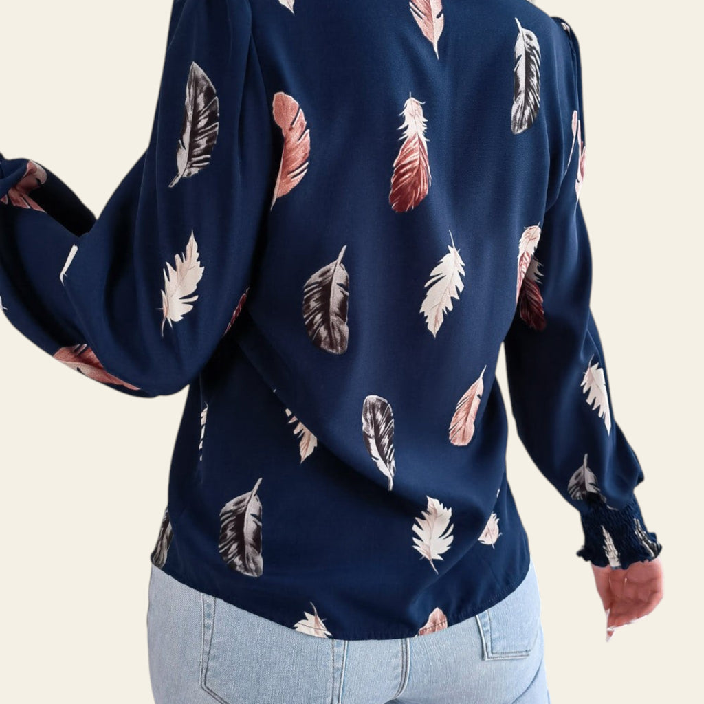 Navy blue blouse with feather pattern worn by a person indoors.