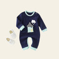 Navy baby romper with cloud and house design on a white surface