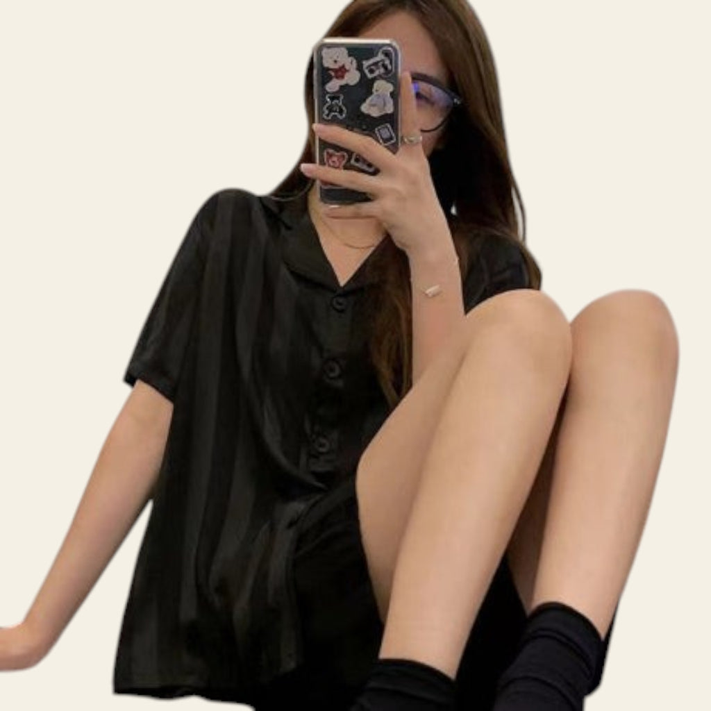 Person wearing a black outfit sitting on a bed with a phone case featuring cartoon characters.