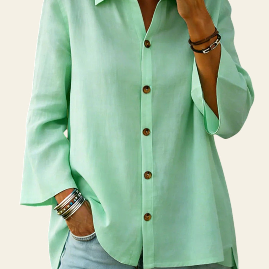 Person wearing a light green button-up shirt and light blue jeans with a blurred background
