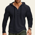 Man wearing a black long-sleeve henley shirt with a blurred background