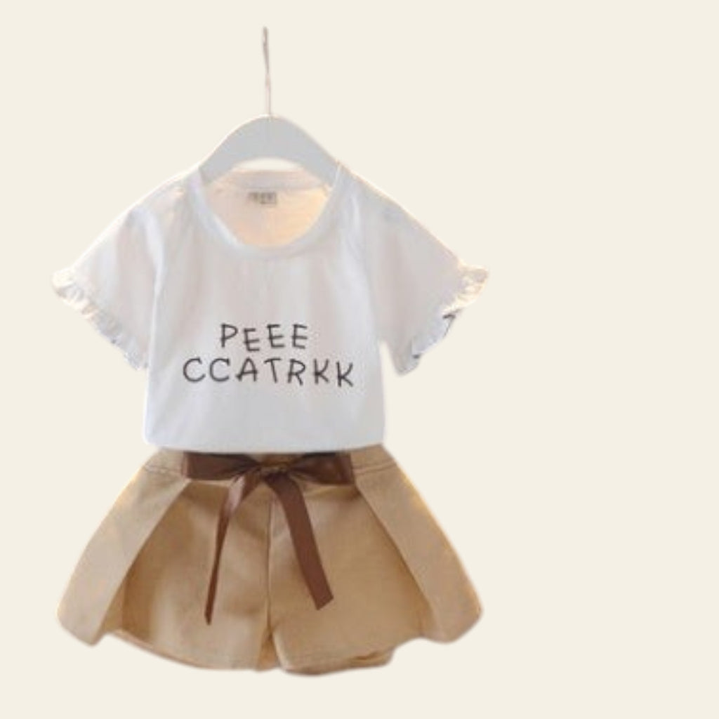 Children's outfit with white shirt and beige shorts on a hanger against a gray background