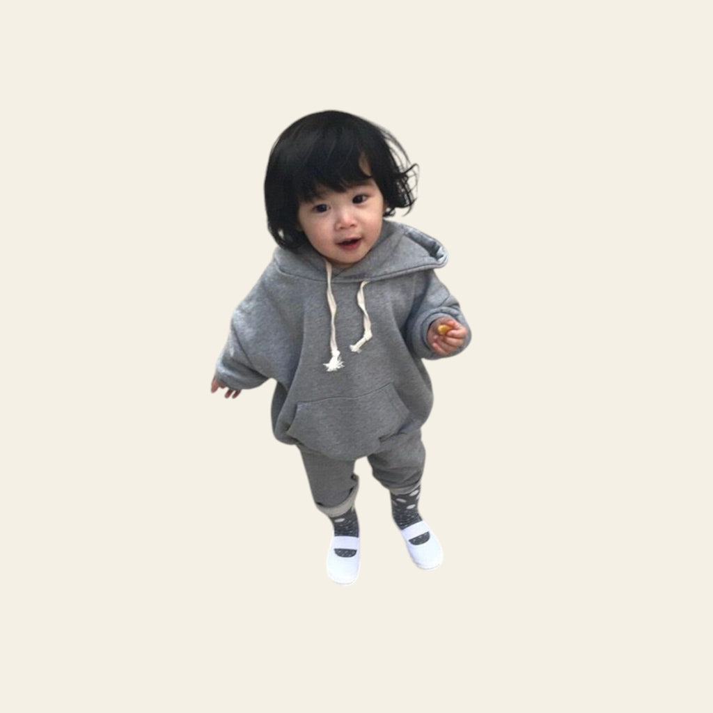 Child wearing a gray hoodie and pants on a concrete surface