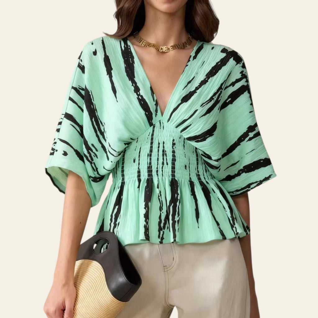 Woman wearing a green blouse with black abstract patterns on a beige background