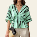 Woman wearing a green blouse with black abstract patterns on a beige background