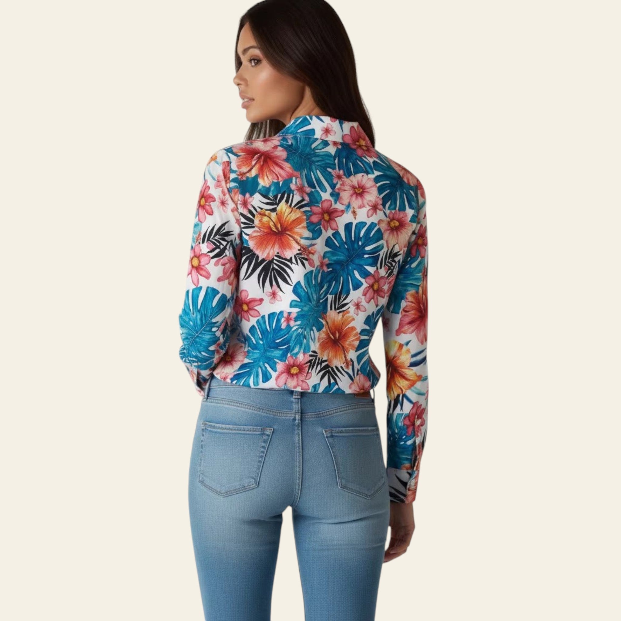 Woman wearing a colorful floral long-sleeve top and blue jeans on a plain background