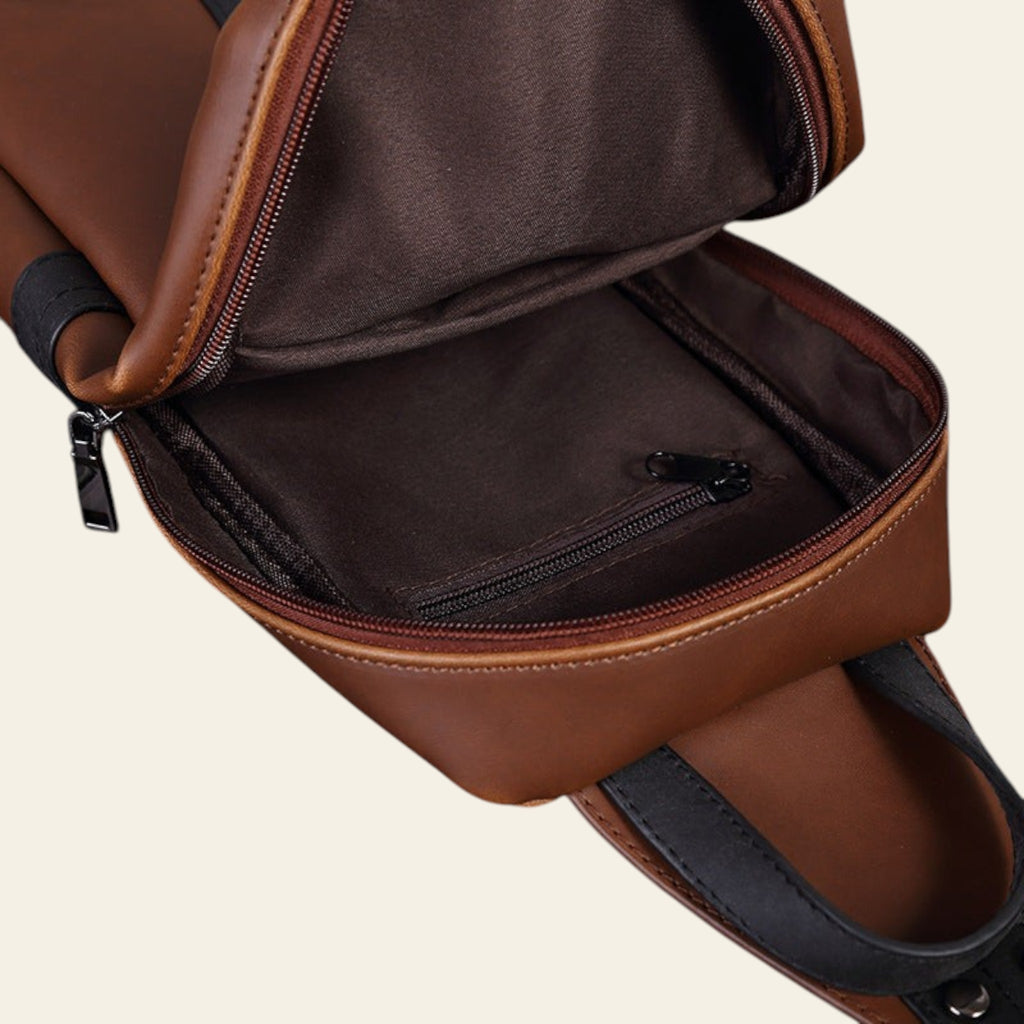 Brown leather backpack with open front pocket on a wooden surface