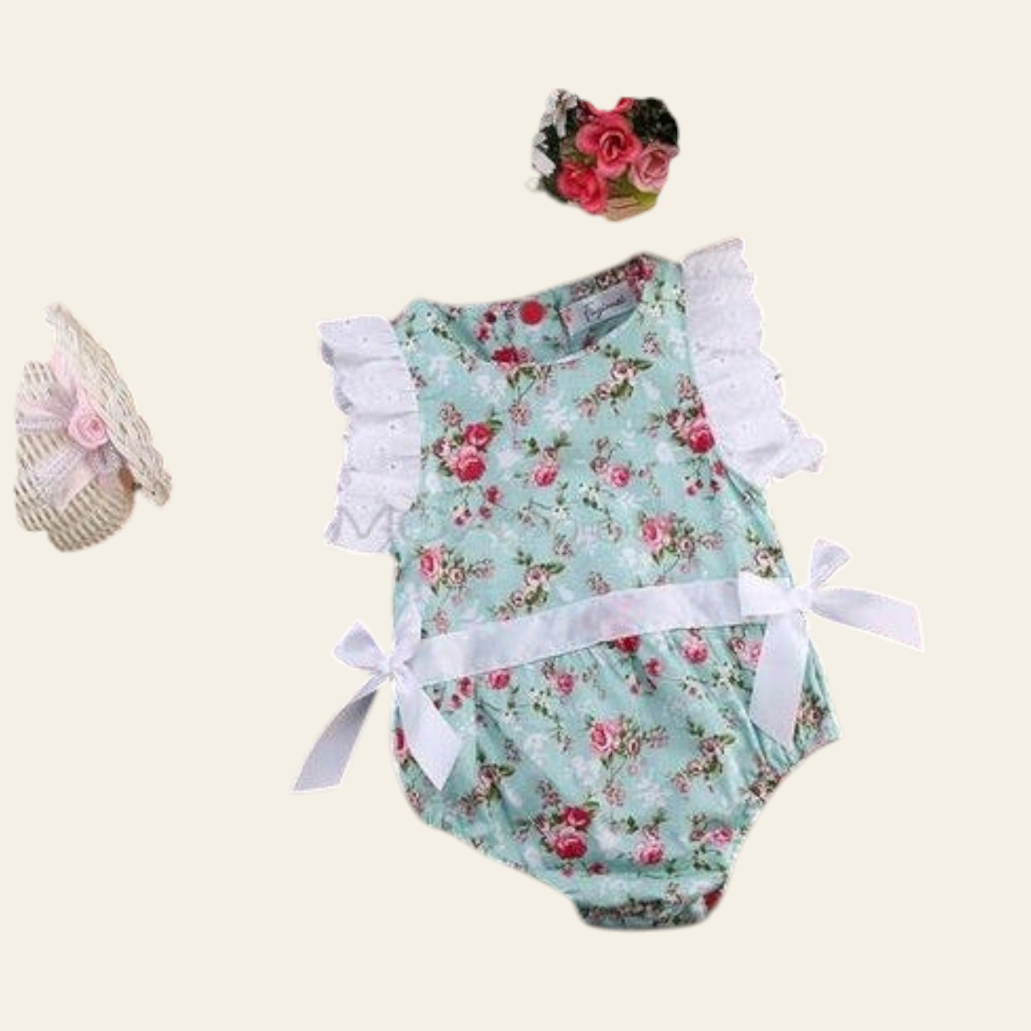Floral baby romper with white ruffles on a wooden surface