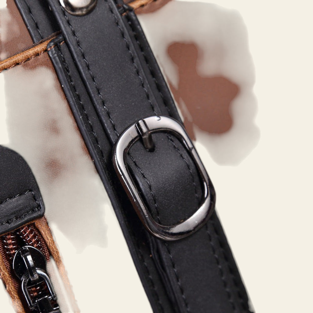 Close-up of a brown leather bag with a black strap and silver buckle.