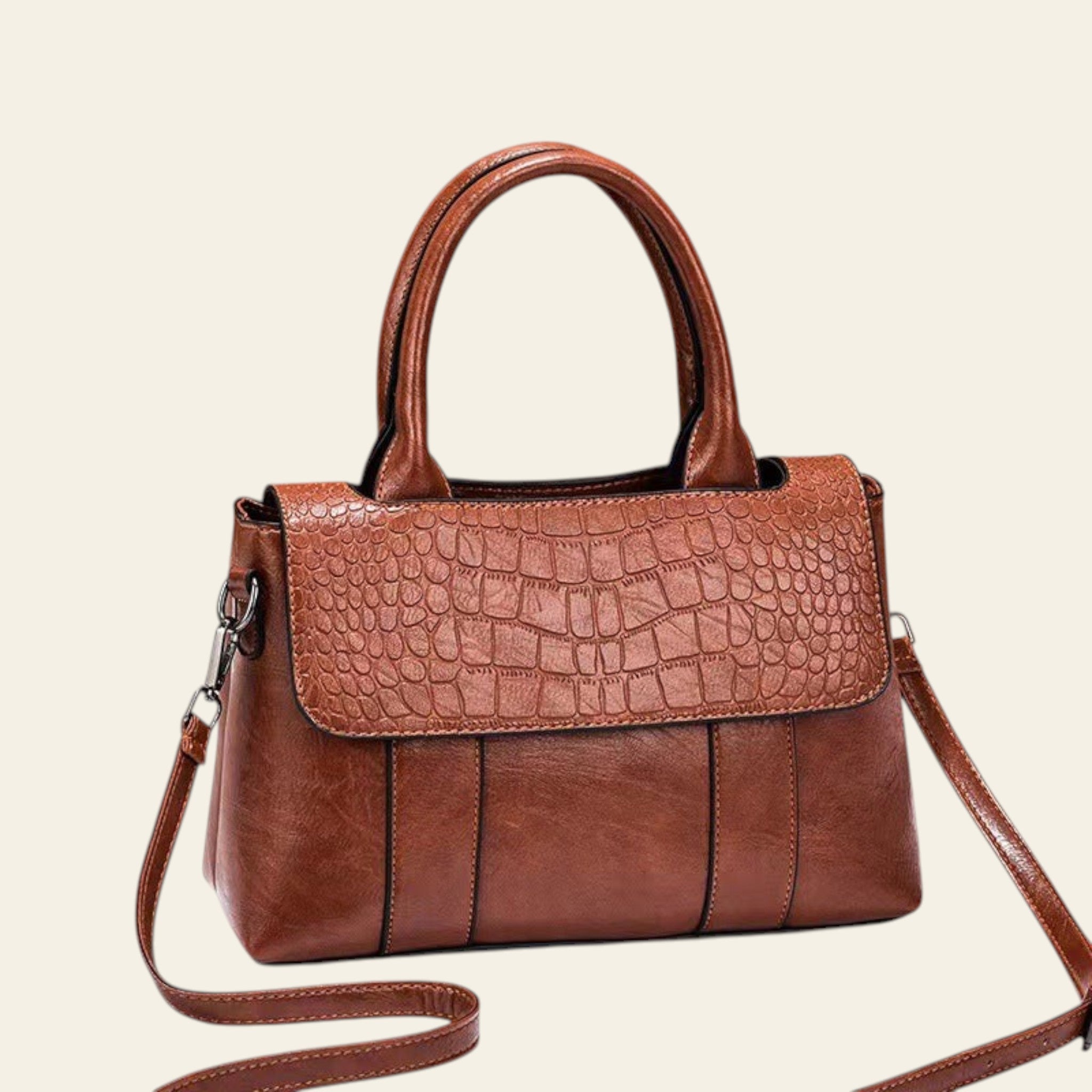 Brown handbag with crocodile texture on a white surface with a brown background