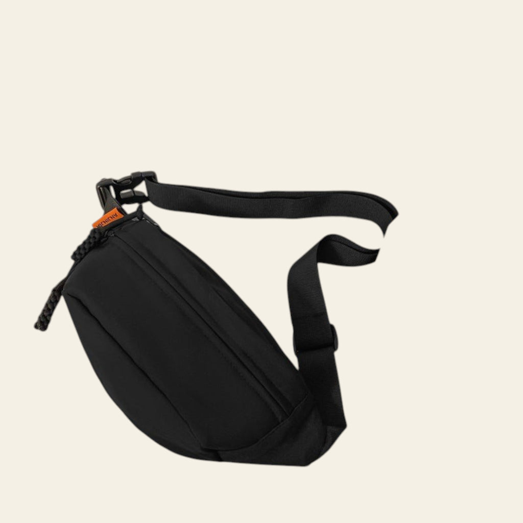 Black waist bag on a glass surface with a book and wooden object in the background