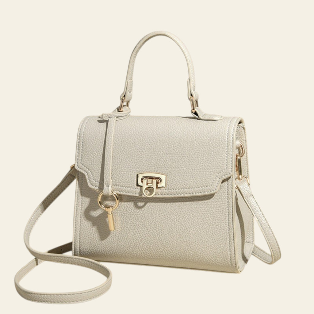 Light gray handbag with a gold clasp on a beige background