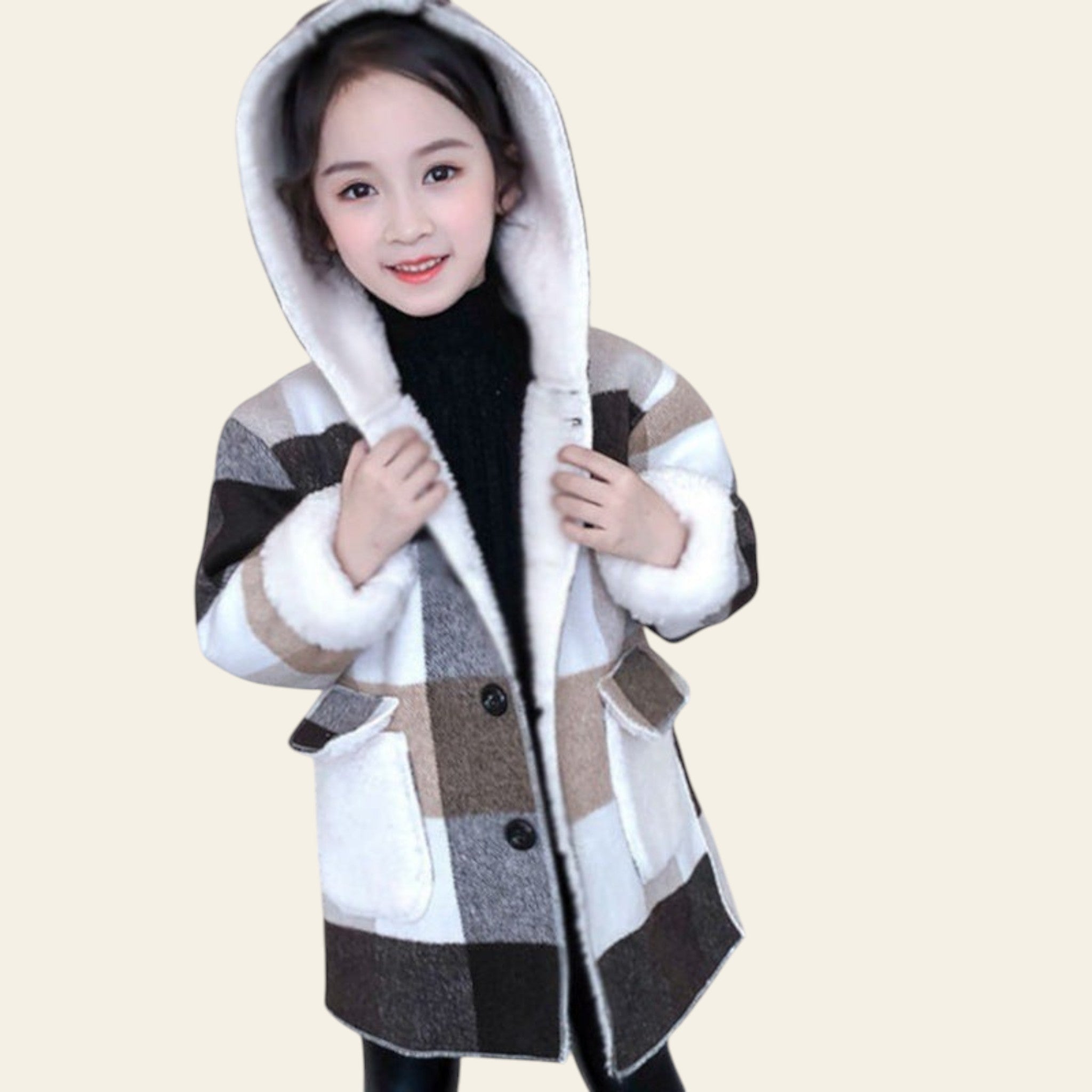 Child wearing a checkered coat with a hood, standing indoors next to a white bucket with pink flowers.