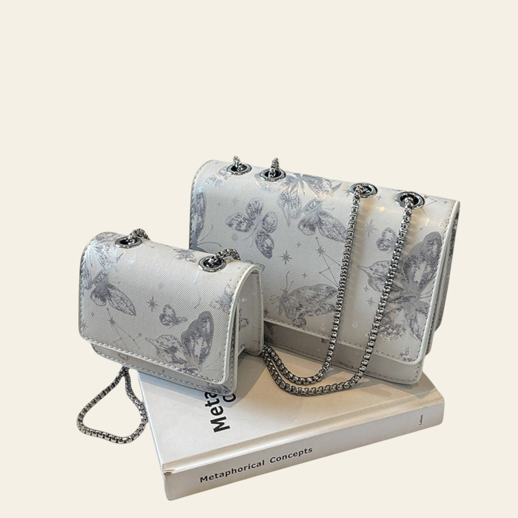 Two silver handbags with butterfly patterns on a book with a 'THANK YOU' bag in the background.
