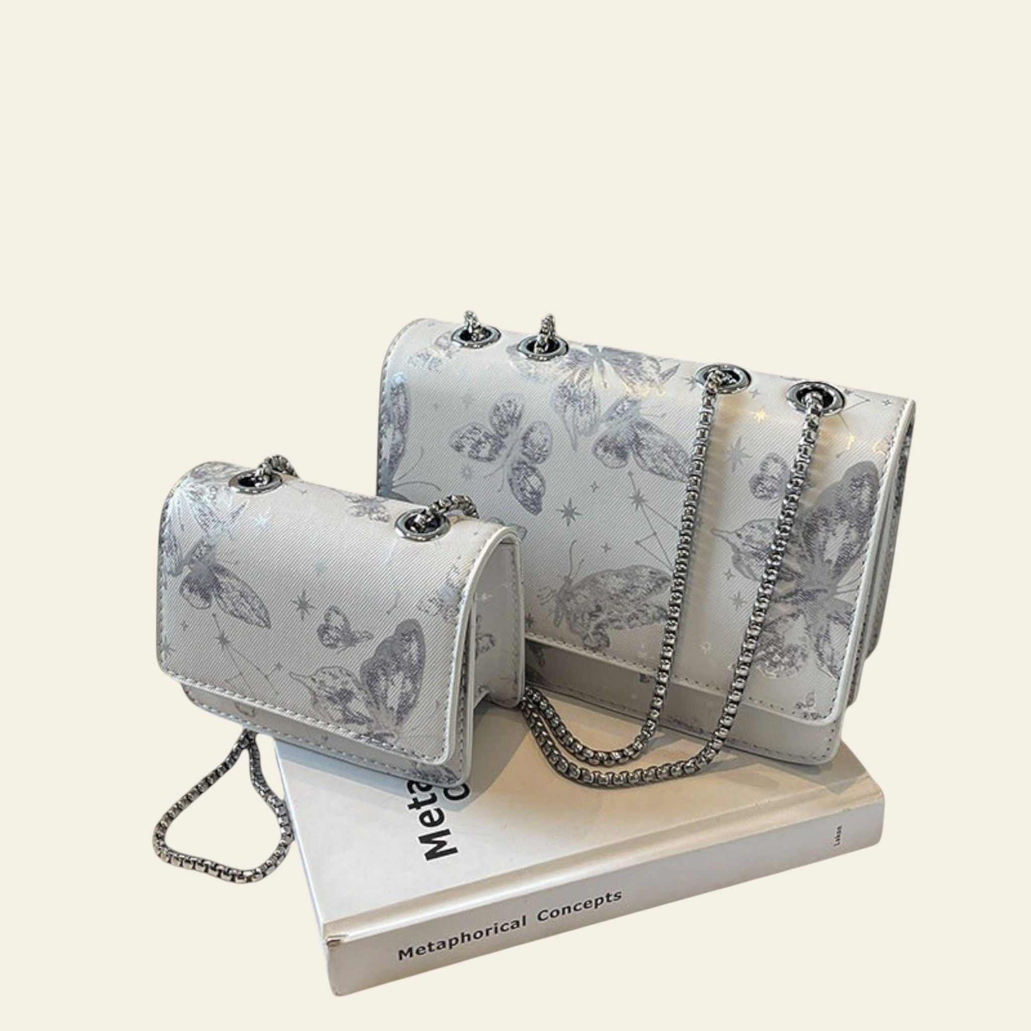 Two silver handbags with butterfly patterns on a book with a 'THANK YOU' bag in the background.