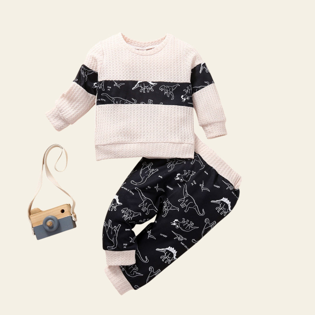 Children's outfit with patterned shirt and pants on a wooden surface with decorative elements.