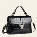 Black crocodile-patterned handbag on a light surface with a neutral background