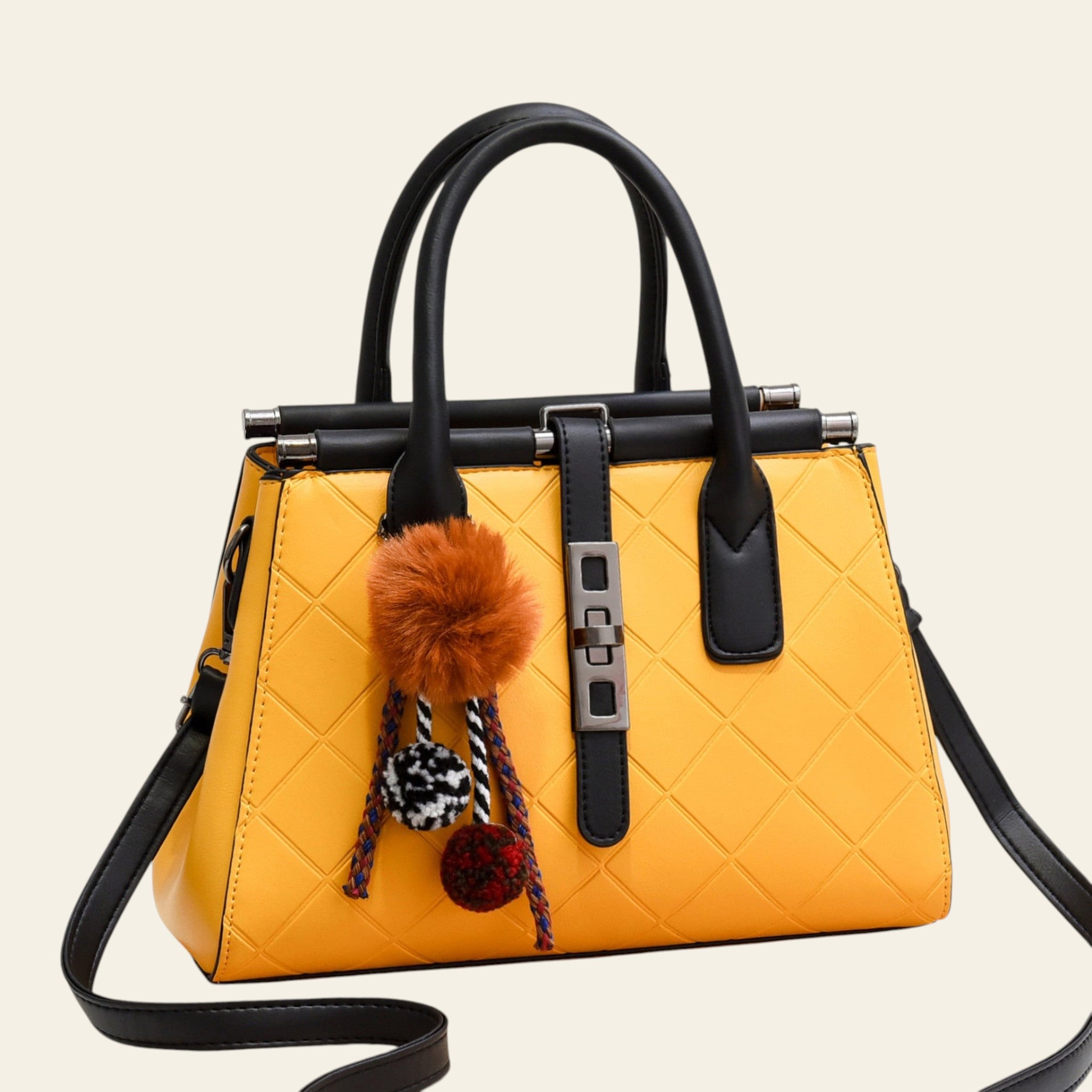 Yellow quilted handbag with black handles and decorative pom-poms on a white background
