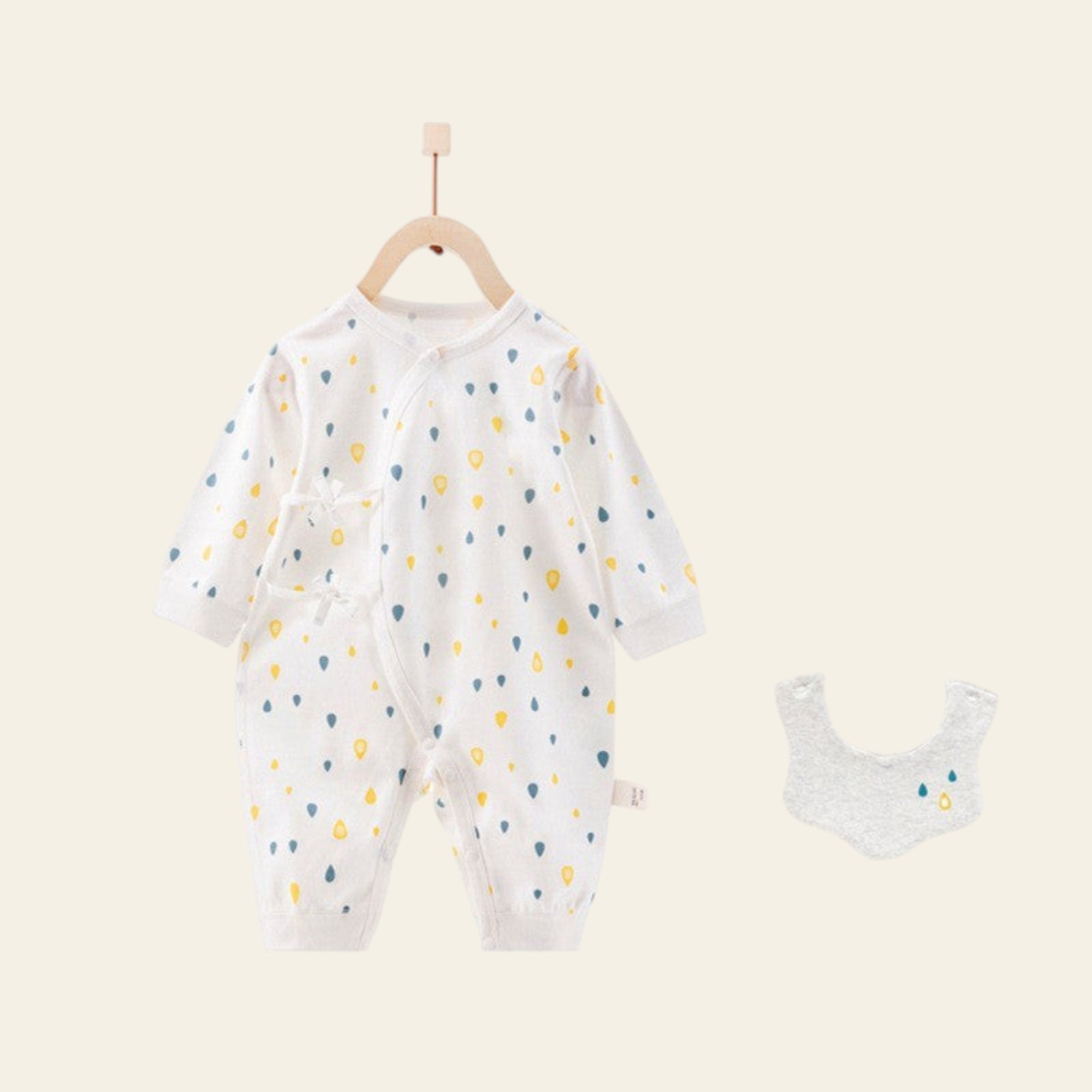 Baby onesie with colorful polka dots and matching bib on a hanger against a white background.