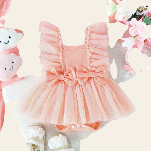 Pink baby romper with ruffles and a bow, surrounded by flowers and toys on a light background