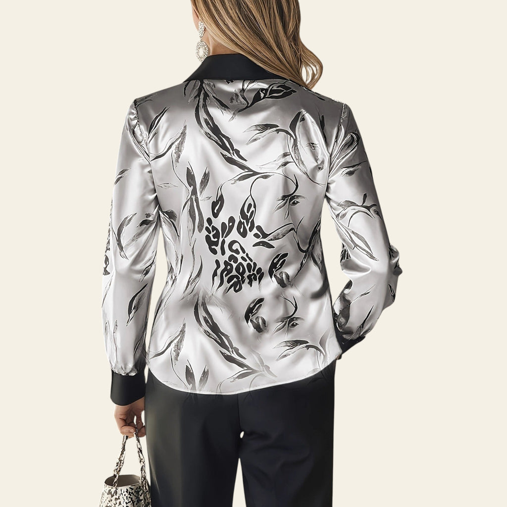 Person wearing a silver floral patterned blouse with a blurred background
