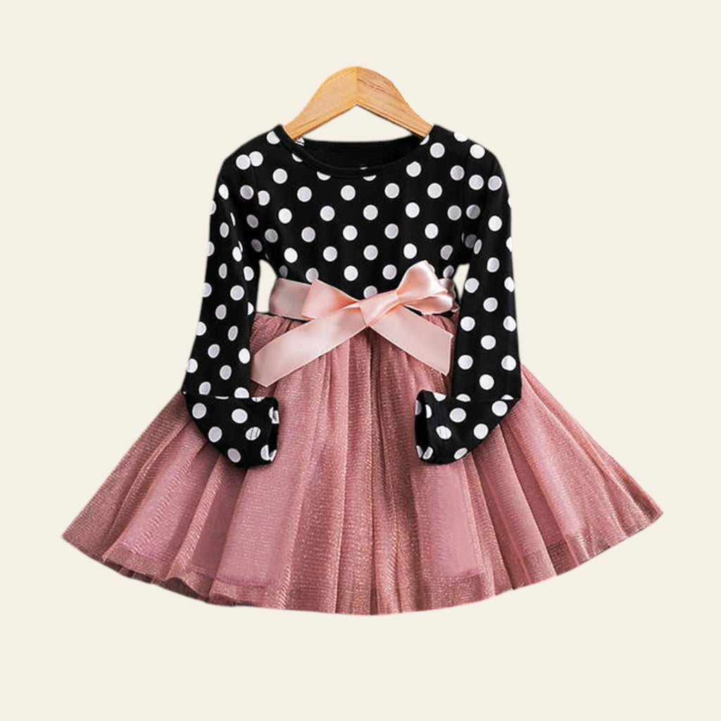 Children's outfit with polka dot top and pink skirt on a wooden surface.