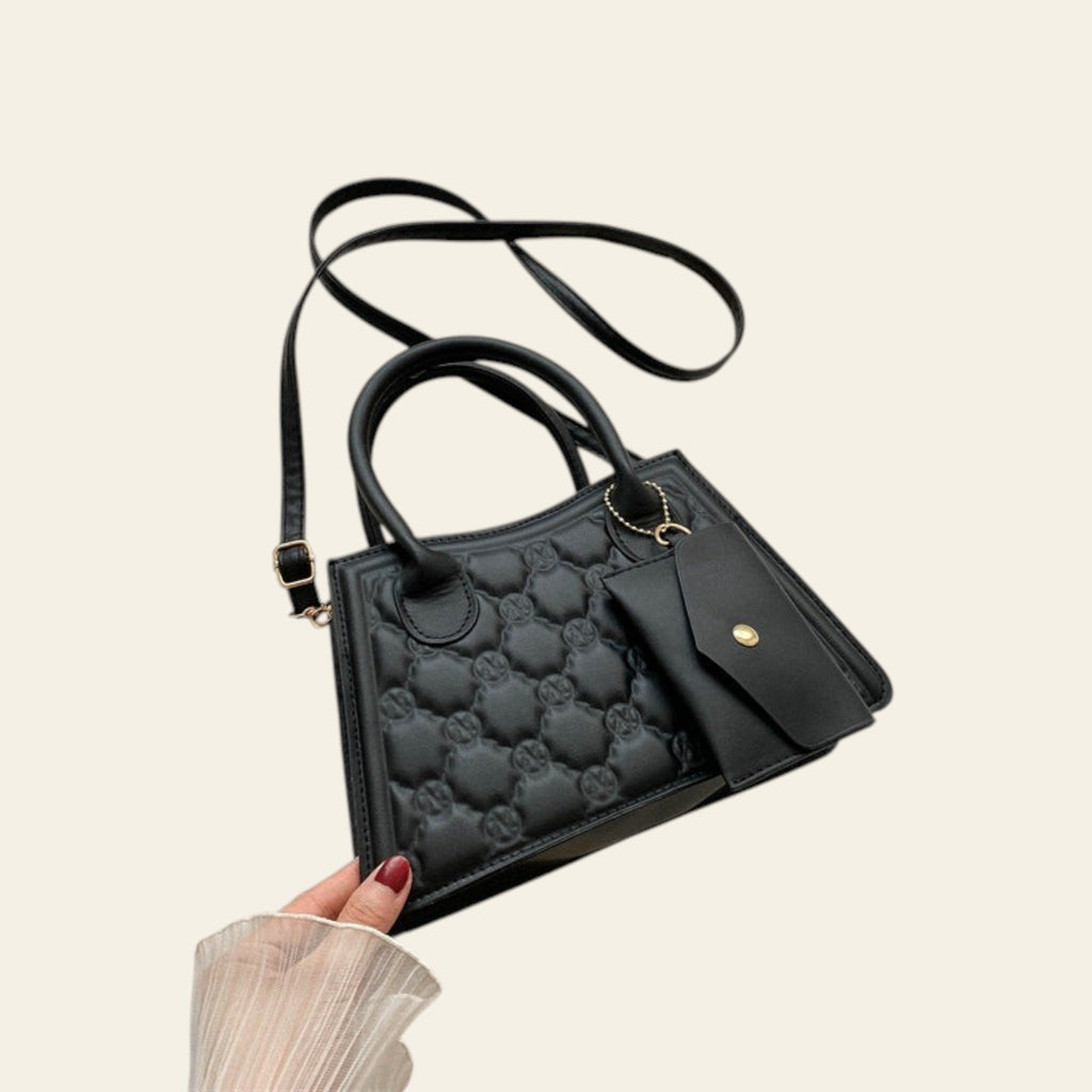Black quilted handbag with gold accents on a light beige background