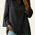 Person wearing a dark gray button-up shirt and light blue jeans with a blurred background