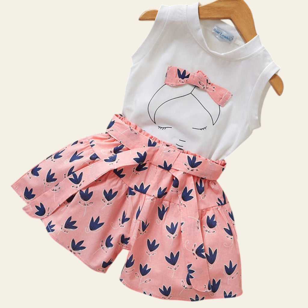 Children's outfit with white top and pink skirt on a wooden surface