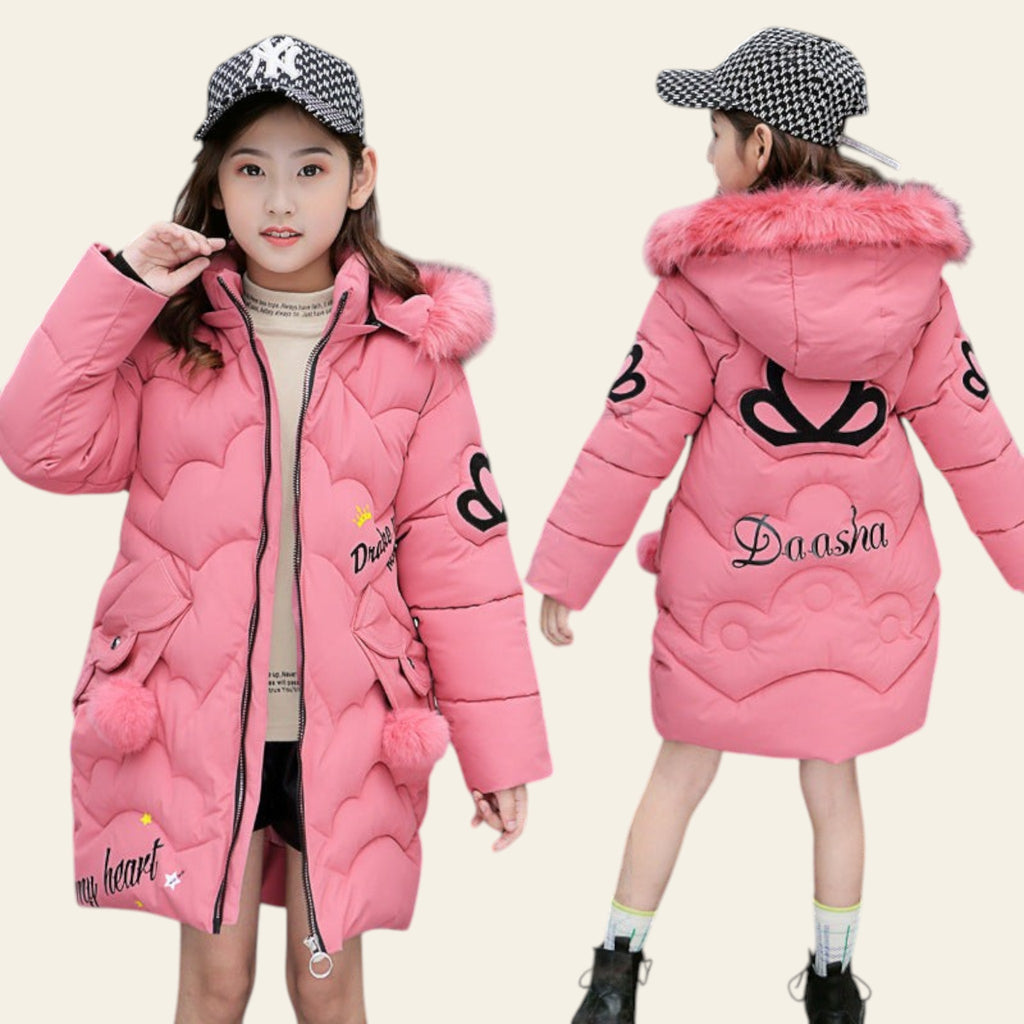 Two children wearing pink winter coats with fur-lined hoods in an urban setting.