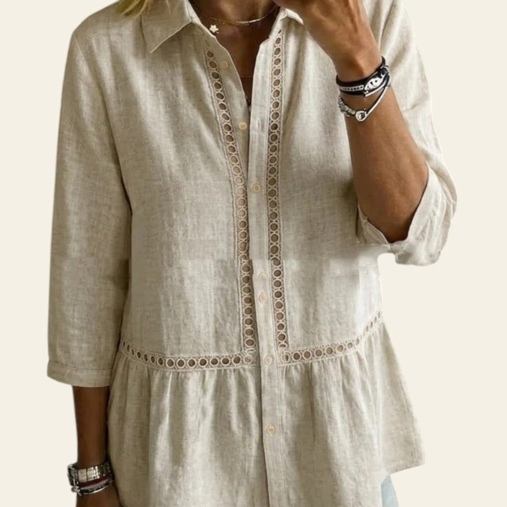 Person wearing a beige linen shirt with intricate embroidery in a home setting.