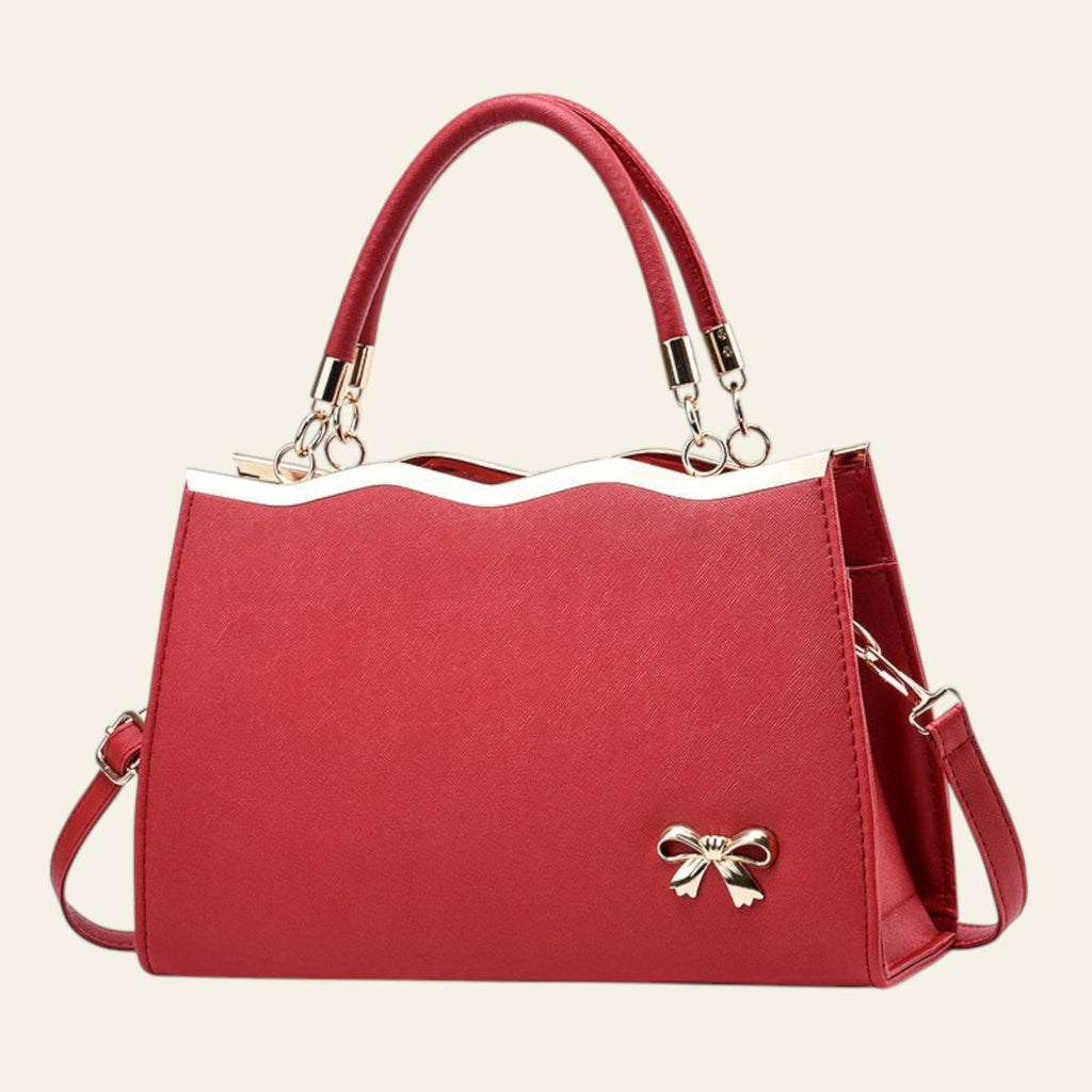 Red handbag with a gold bow detail on a white background