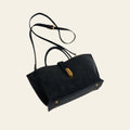 Black handbag with gold accents on a white surface with gray fabric