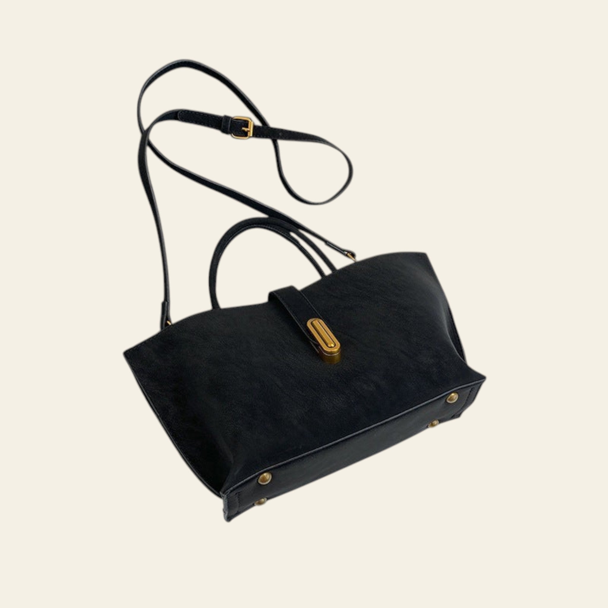 Black handbag with gold accents on a white surface with gray fabric