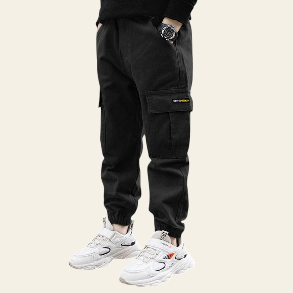 Person wearing black cargo pants and white sneakers on a street.
