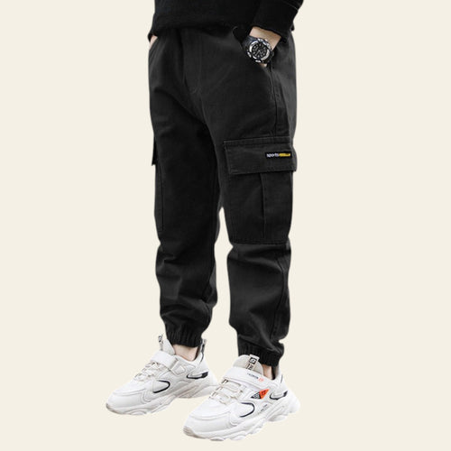 Person wearing black cargo pants and white sneakers on a street.