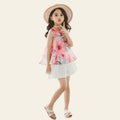 Young girl in a floral dress and straw hat standing on a textured surface.