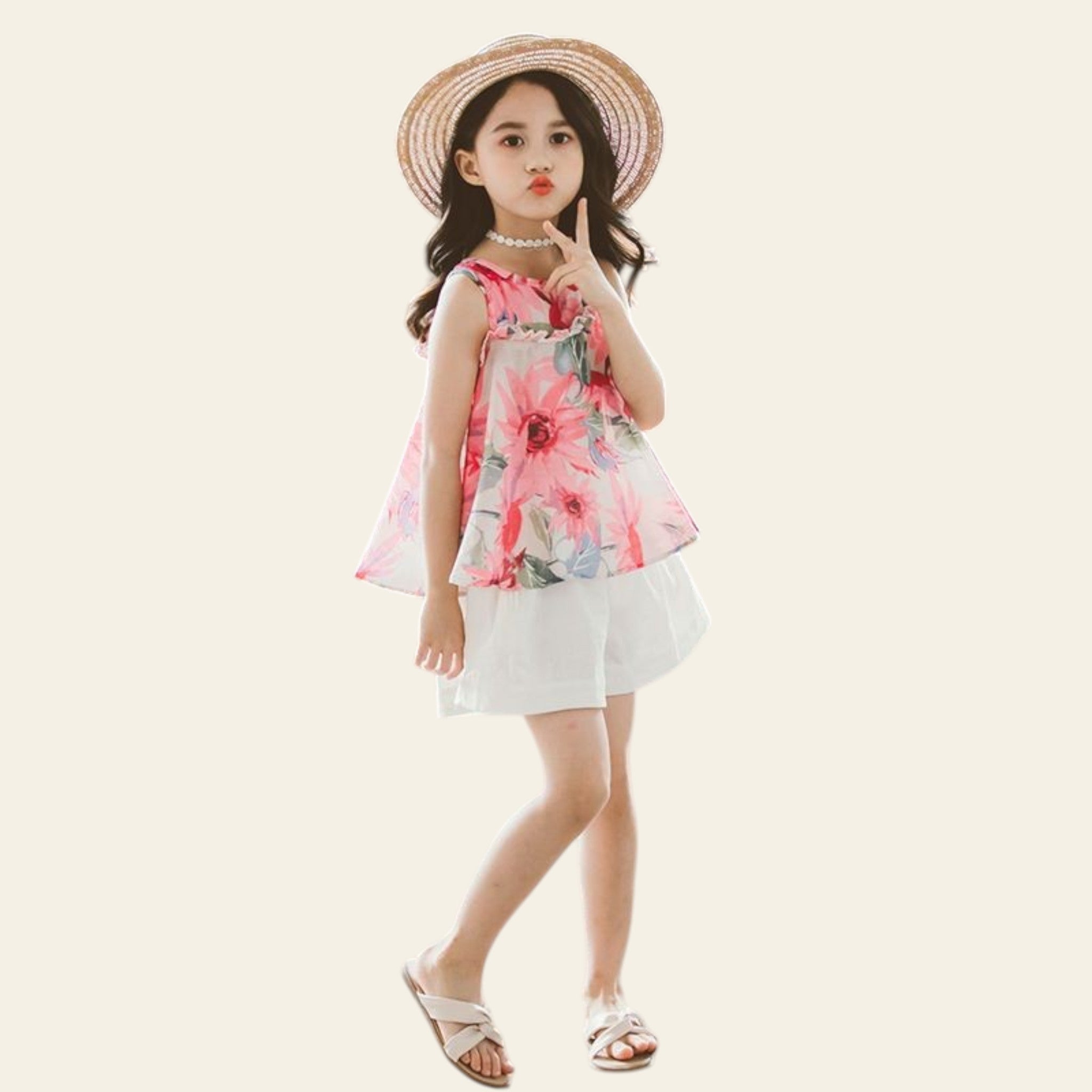 Young girl in a floral dress and straw hat standing on a textured surface.