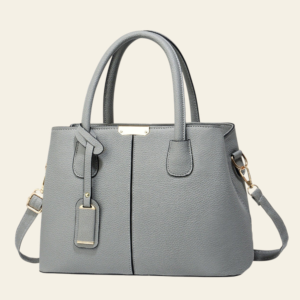Gray handbag with gold accents on a light gray background