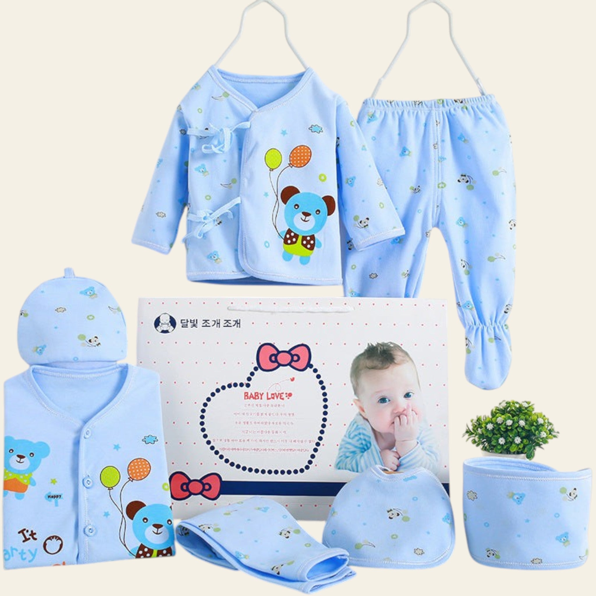Baby clothing set with blue bear design, including a hat, onesie, pants, and more, displayed against a white background.
