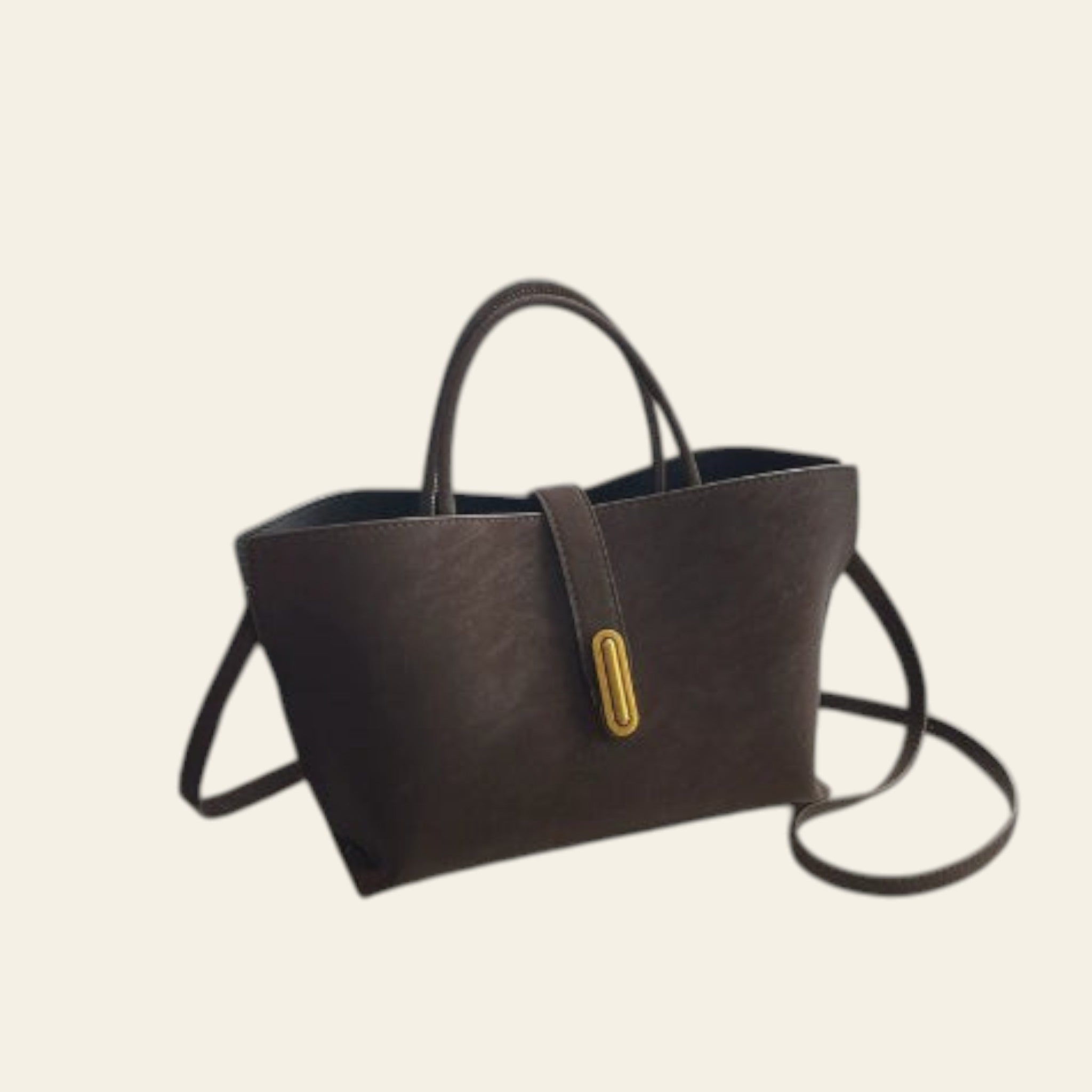 Brown leather handbag with a gold clasp on a light-colored surface.