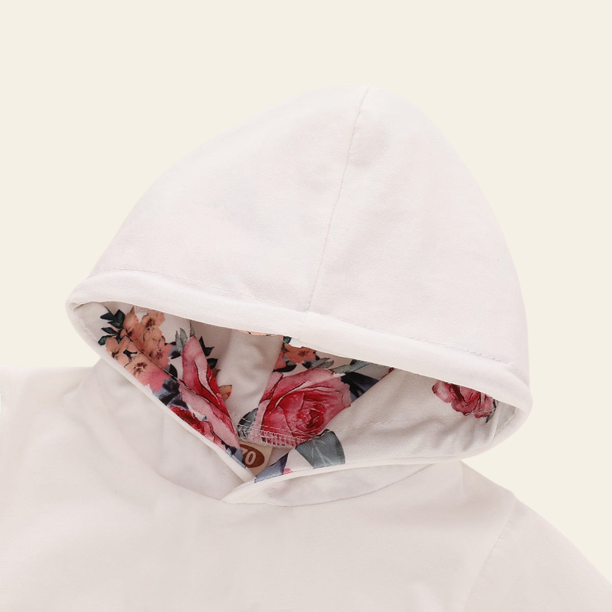 Floral lining peeking out from under a white hooded garment on a light background
