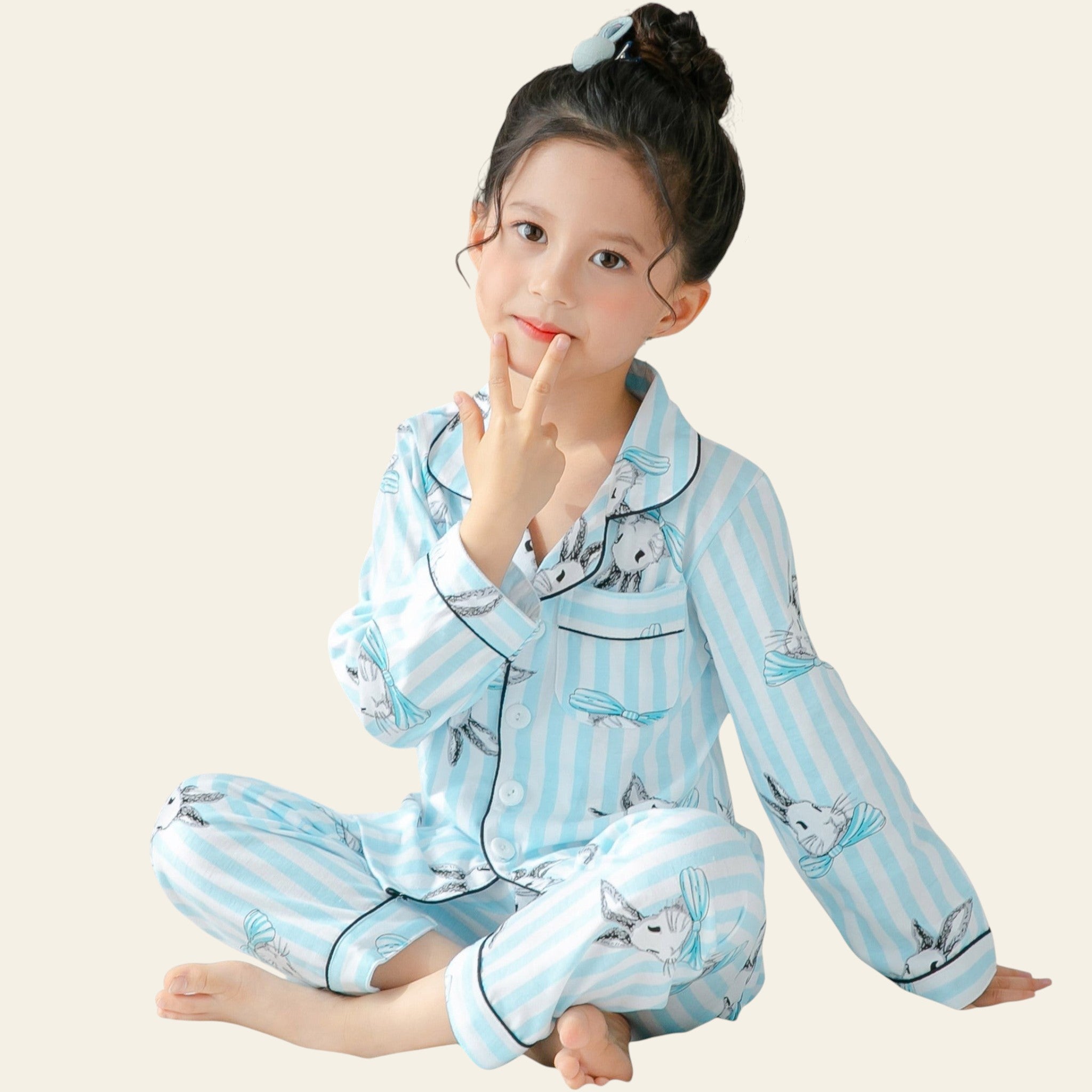 Child wearing blue striped pajamas with animal prints, sitting on a bed.
