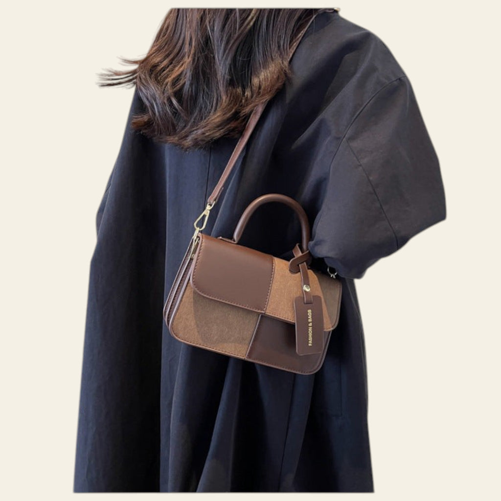 Person wearing a brown and black handbag against a neutral background