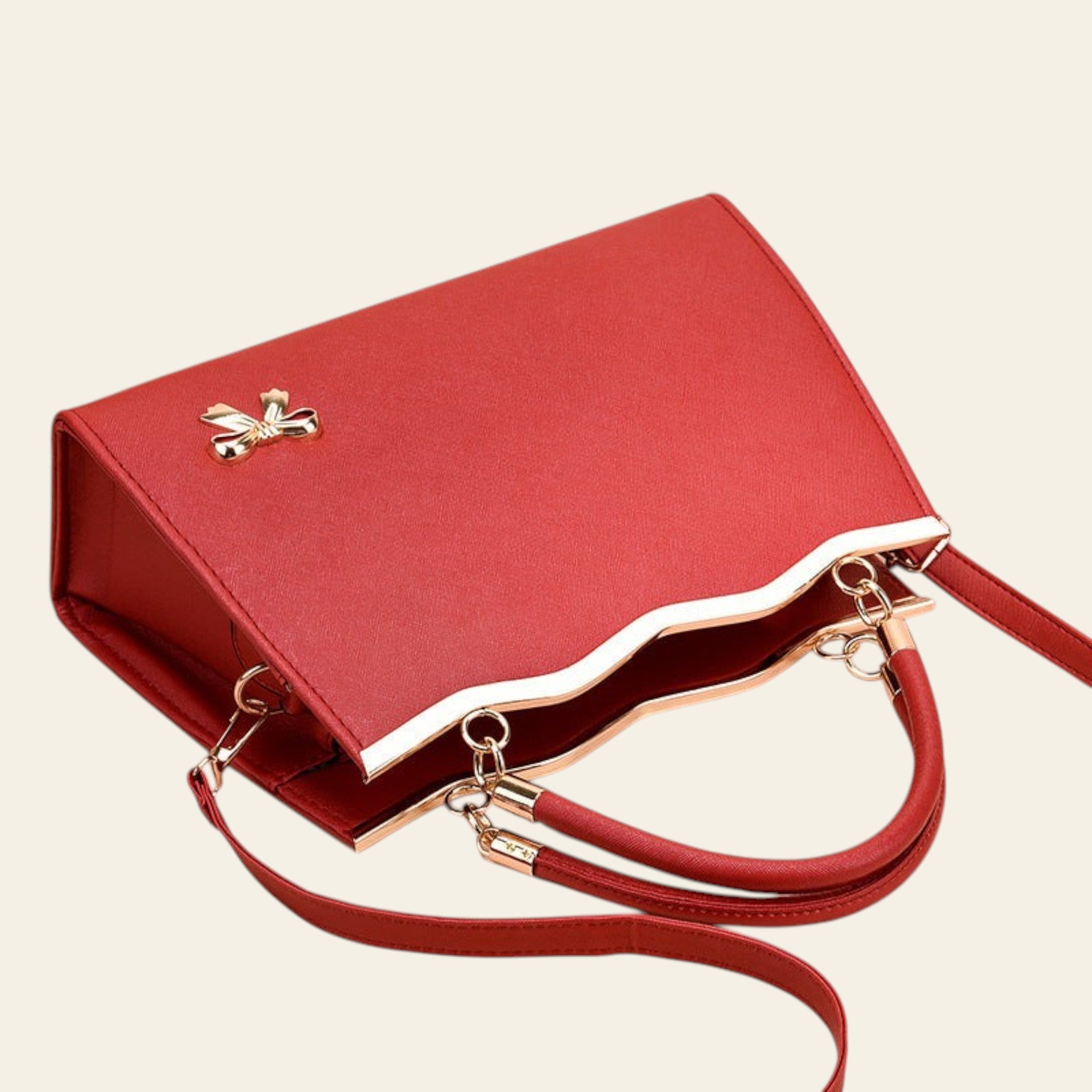 Red handbag with gold accents on a beige background
