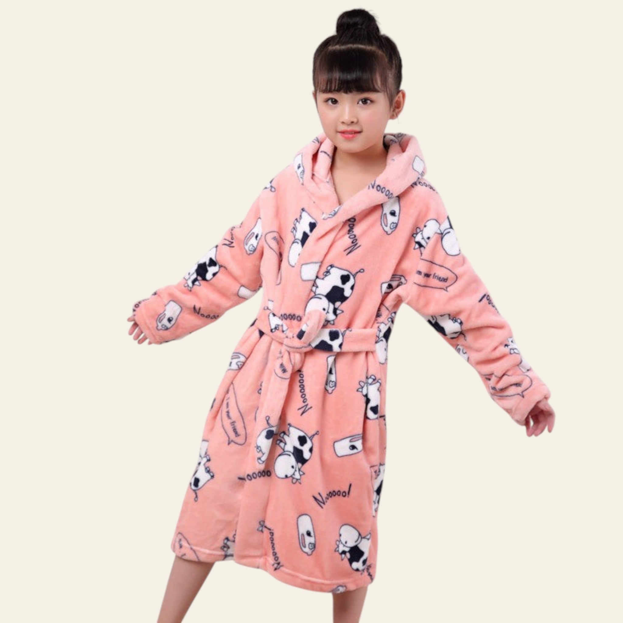 Child wearing a pink robe with cartoon cow patterns on a plain background
