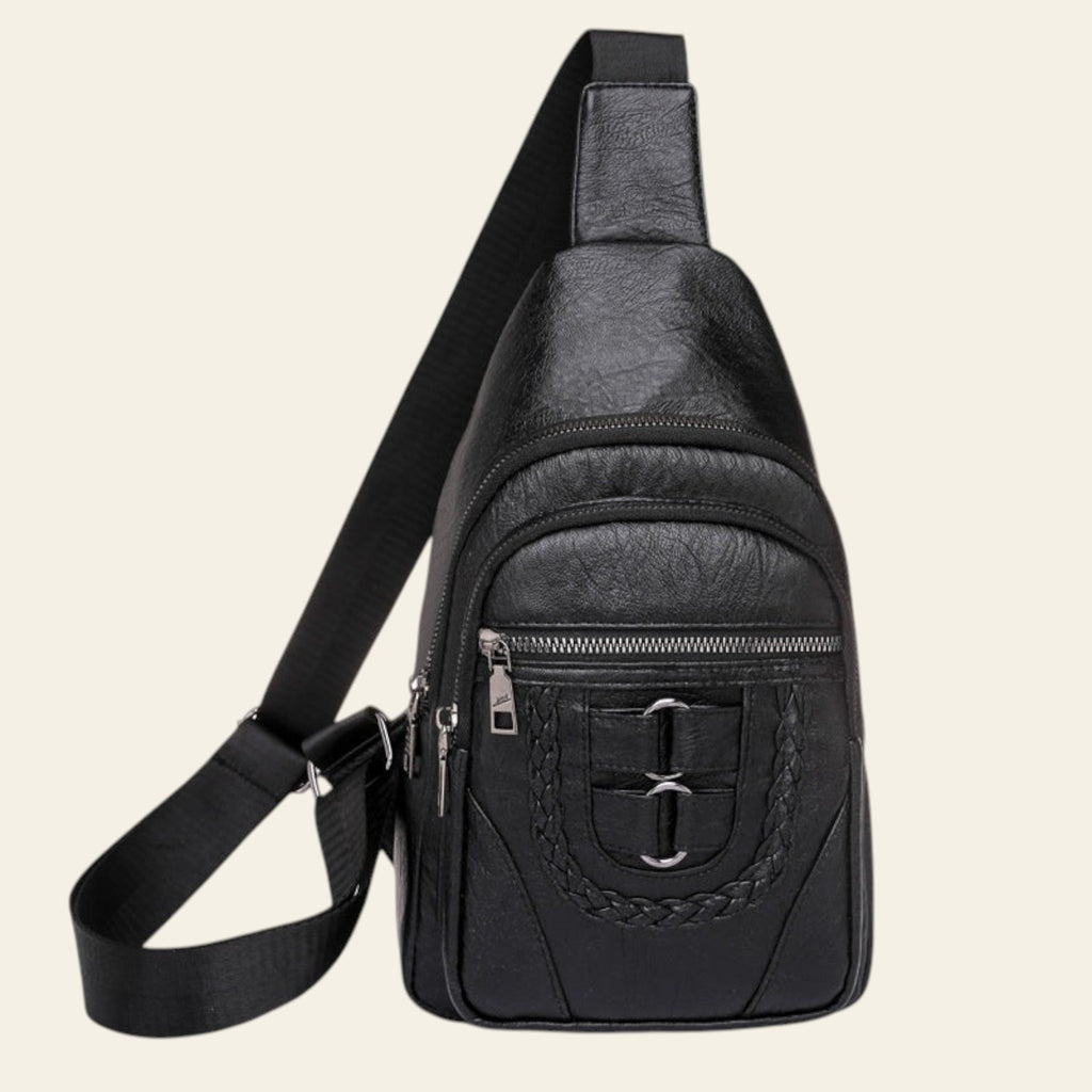 Black leather sling bag with multiple zippers on a white background