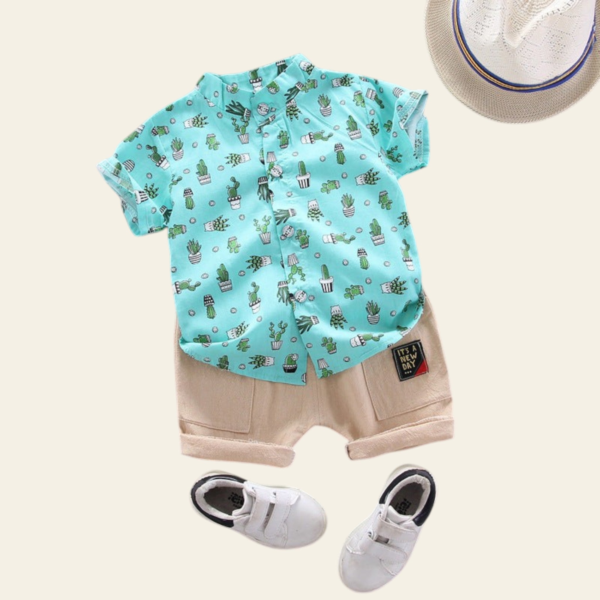 Children's outfit with a cactus-patterned shirt, beige shorts, and white sneakers on a gray background.