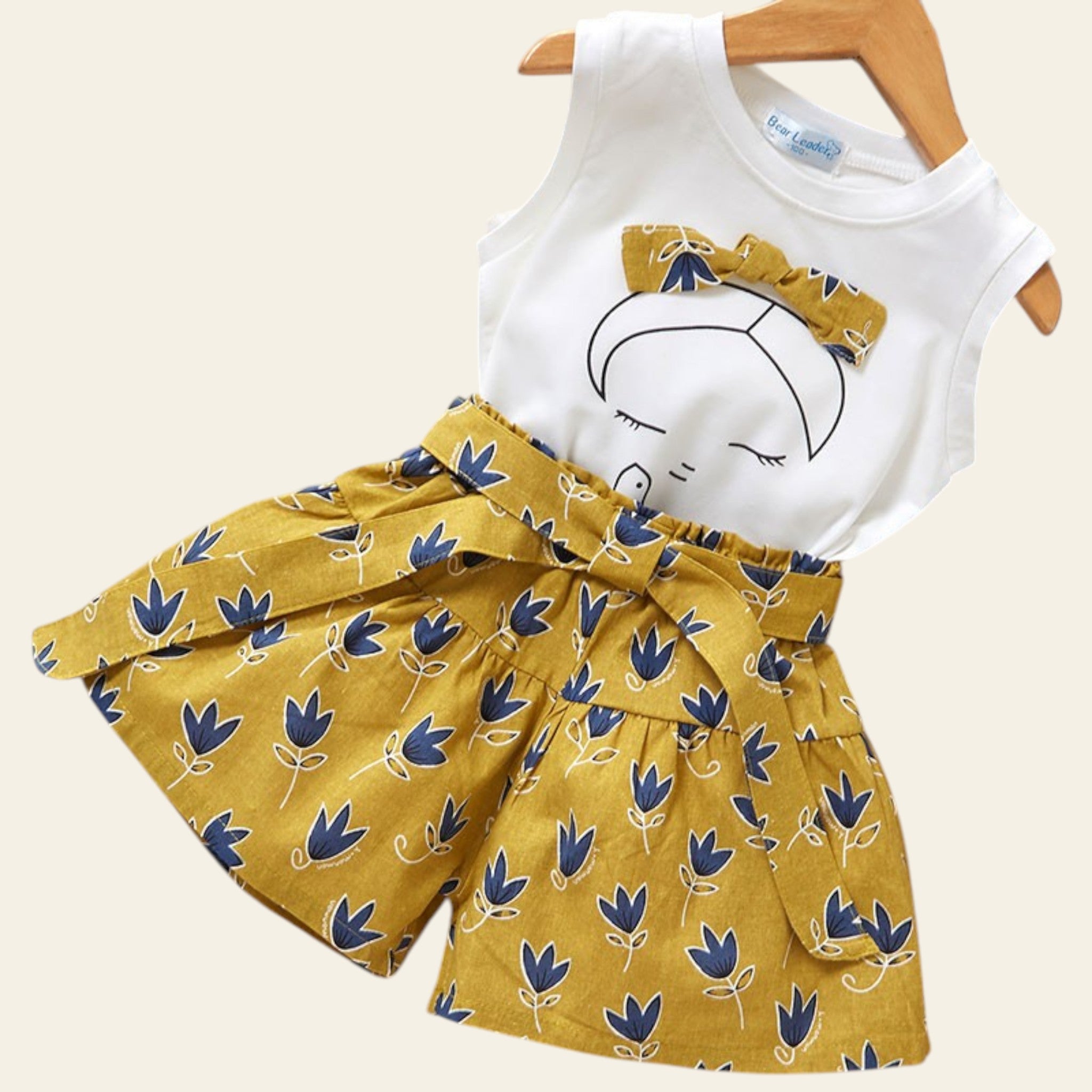 Children's outfit with white top and yellow floral skirt on a wooden surface