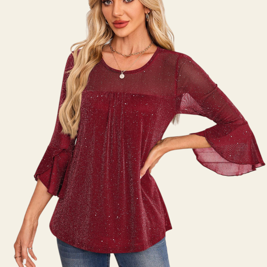 Woman wearing a burgundy blouse with bell sleeves in an elegant interior setting